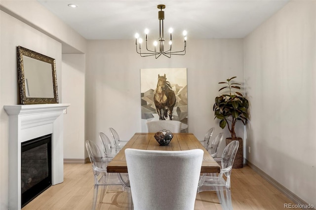 15252 W Warren Dr, Lakewood, CO 80228 - dining space with an inviting chandelier, baseboards, a glass covered fireplace, and light wood finished floors