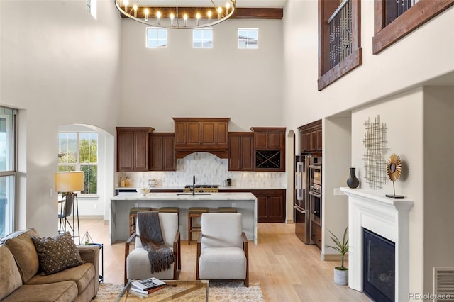 15252 W Warren Dr, Lakewood, CO 80228 - living room featuring light wood-type flooring, a towering ceiling, a notable chandelier, and visible vents