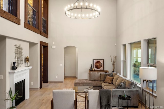 15252 W Warren Dr, Lakewood, CO 80228 - living area with arched walkways, a high ceiling, an inviting chandelier, and wood finished floors