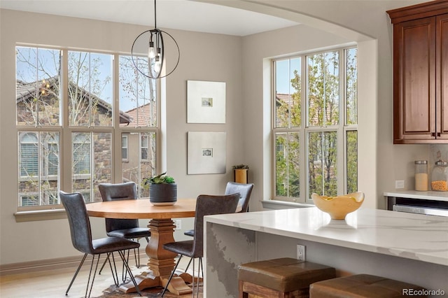 15252 W Warren Dr, Lakewood, CO 80228 - dining area with arched walkways, plenty of natural light, baseboards, and light wood-style flooring