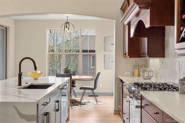 15252 W Warren Dr, Lakewood, CO 80228 - kitchen featuring light stone counters, a sink, light wood finished floors, decorative light fixtures, and stainless steel appliances