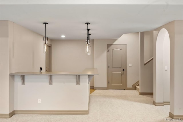 15252 W Warren Dr, Lakewood, CO 80228 - kitchen with a kitchen bar, hanging light fixtures, baseboards, a peninsula, and light carpet