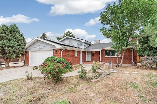 206 Troy St, Aurora, CO 80011 - view of front of house with brick siding, an attached garage, roof mounted solar panels, and driveway