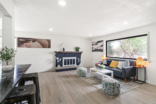 206 Troy St, Aurora, CO 80011 - living area with wood finished floors, a textured ceiling, recessed lighting, and a glass covered fireplace