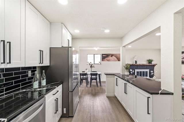 206 Troy St, Aurora, CO 80011 - kitchen with stainless steel appliances, light wood-style flooring, white cabinets, backsplash, and recessed lighting