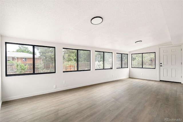206 Troy St, Aurora, CO 80011 - spare room featuring a textured ceiling, wood finished floors, lofted ceiling, and plenty of natural light