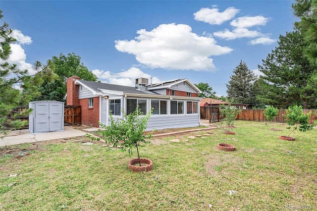 206 Troy St, Aurora, CO 80011 - rear view of property featuring a storage shed, a fenced backyard, a chimney, and a sunroom