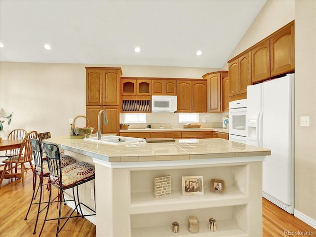 11556 W Cooper Pl, Littleton, CO 80127 - kitchen featuring white appliances, tile countertops, a breakfast bar area, light wood-style floors, and open shelves