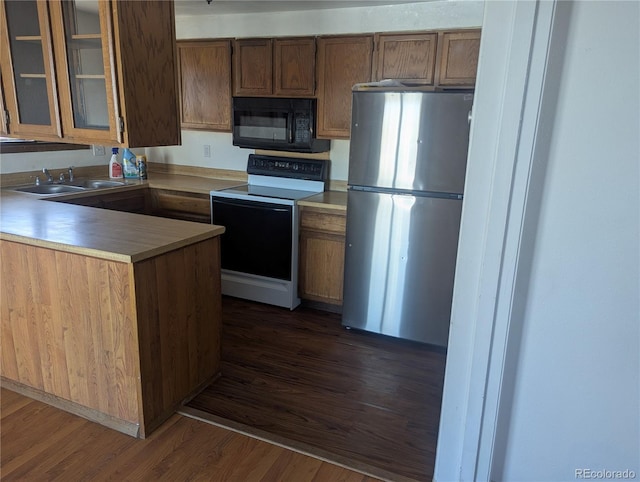 kitchen featuring glass insert cabinets, freestanding refrigerator, a sink, range with electric cooktop, and black microwave