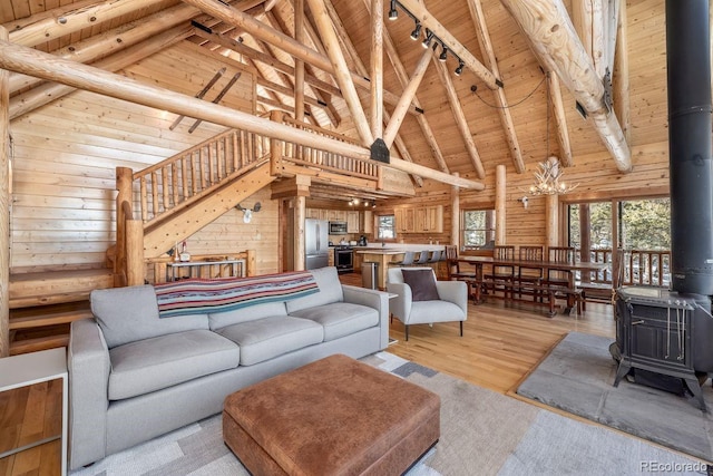 living room featuring light wood finished floors, rail lighting, a wood stove, wooden walls, and wooden ceiling