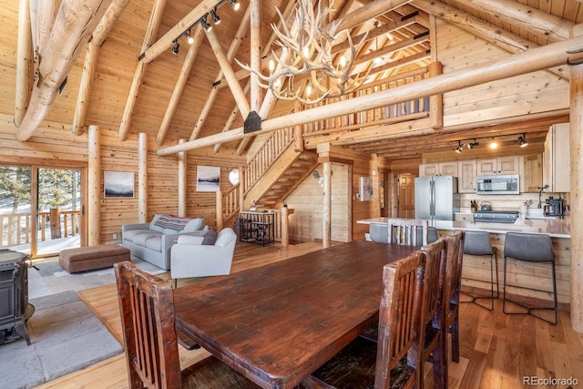 dining space featuring a wood stove, wood walls, high vaulted ceiling, and wood ceiling