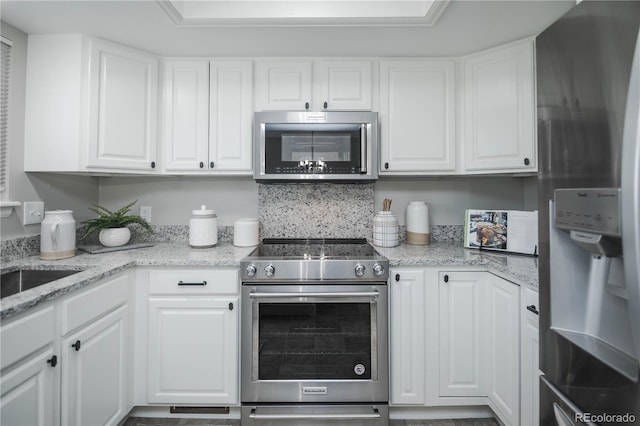 kitchen featuring stainless steel appliances, light stone countertops, and white cabinets