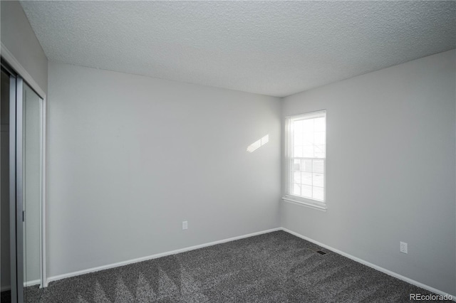 carpeted empty room with a textured ceiling