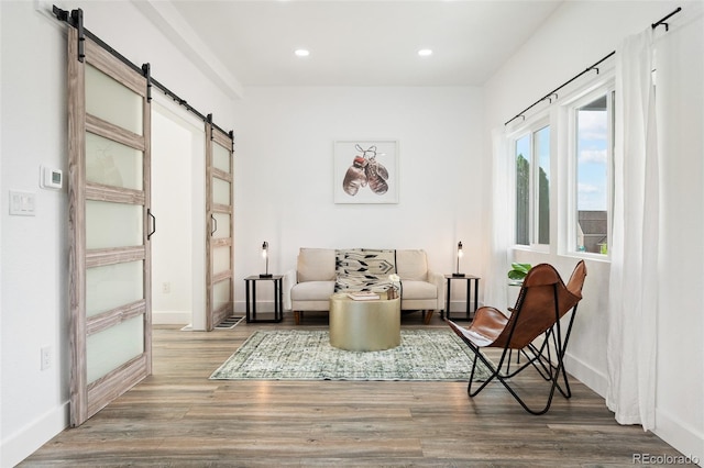 sitting room with wood-type flooring and a barn door