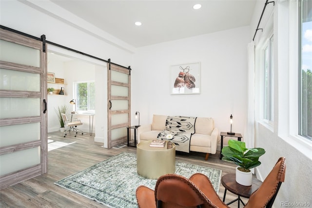 sitting room with a barn door and light hardwood / wood-style floors