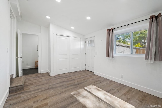 unfurnished bedroom featuring a closet, lofted ceiling, and hardwood / wood-style floors