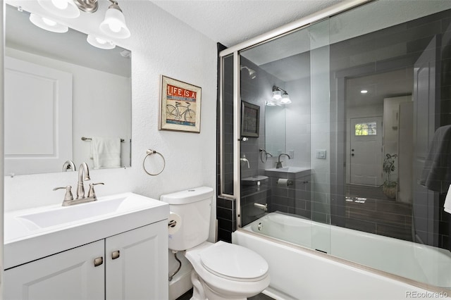 full bathroom with toilet, bath / shower combo with glass door, a textured ceiling, and vanity