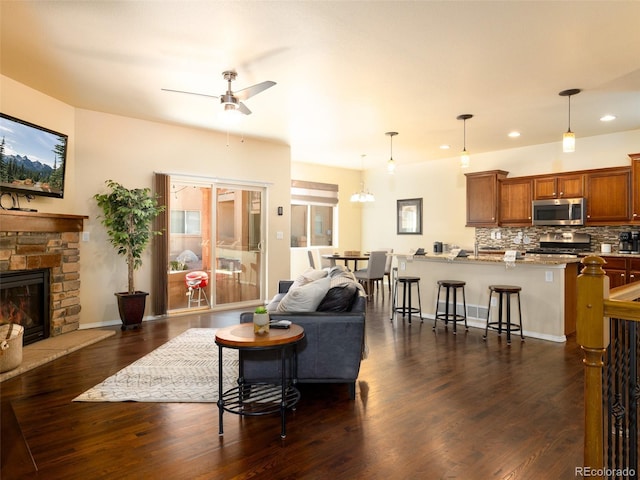 living area with baseboards, recessed lighting, a fireplace, a ceiling fan, and dark wood-style flooring