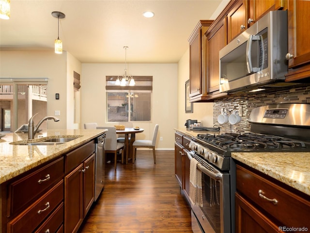 kitchen with dark wood-style flooring, a sink, hanging light fixtures, stainless steel appliances, and tasteful backsplash