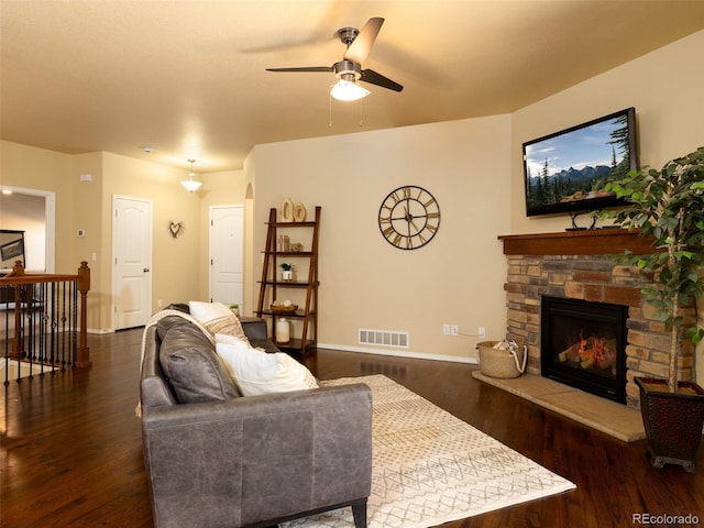 living room with visible vents, baseboards, a stone fireplace, and dark wood-style flooring