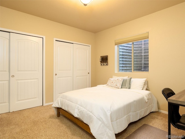 bedroom with carpet flooring, baseboards, and multiple closets