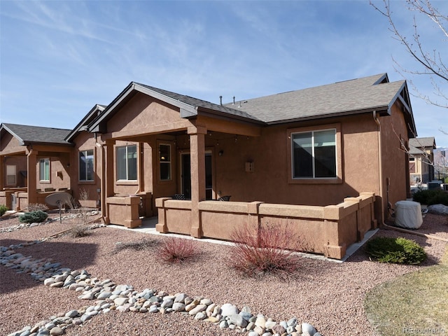 view of front of house featuring a patio area, roof with shingles, and stucco siding