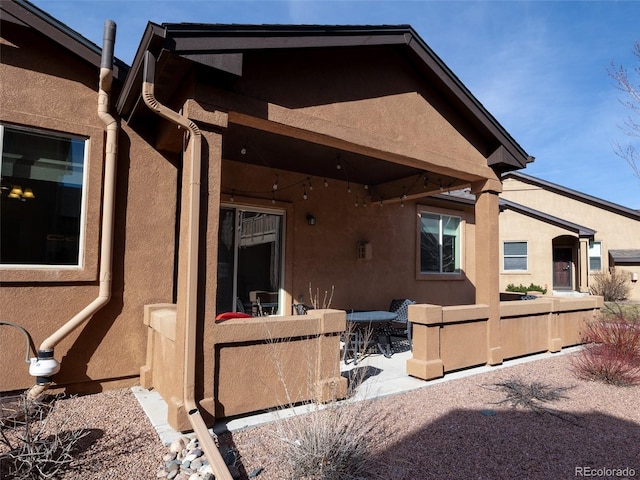 rear view of house featuring a patio area and stucco siding