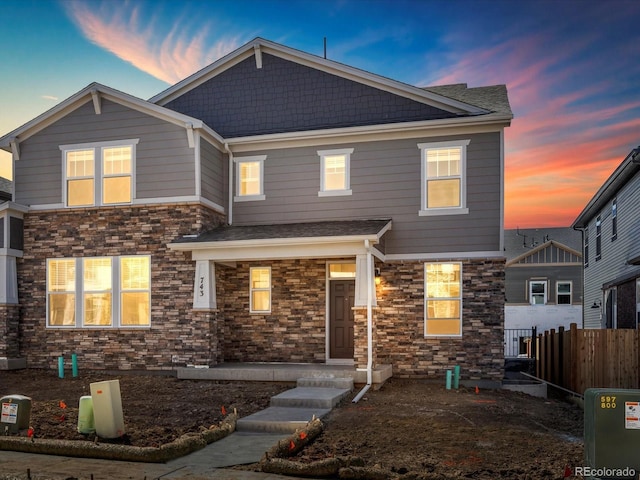 view of front facade with stone siding and fence