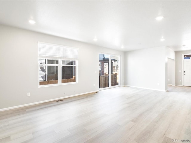 empty room featuring light wood-type flooring, visible vents, baseboards, and recessed lighting