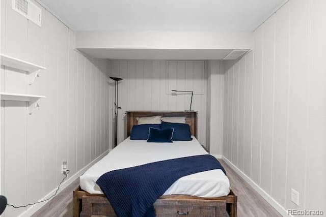 bedroom featuring hardwood / wood-style flooring and wood walls