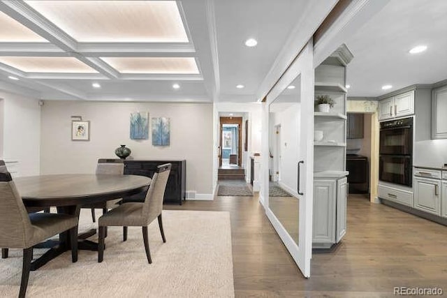 dining room with beam ceiling, light wood-type flooring, and coffered ceiling