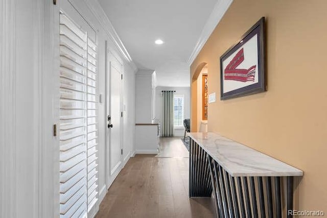 corridor with wood-type flooring and crown molding