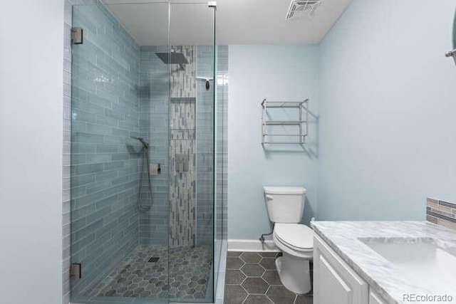 bathroom featuring tile patterned floors, vanity, toilet, and a shower with shower door