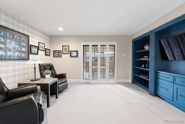 sitting room with built in shelves and light carpet