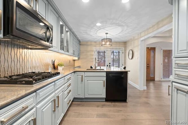 kitchen featuring sink, decorative light fixtures, gray cabinets, black appliances, and light wood-type flooring