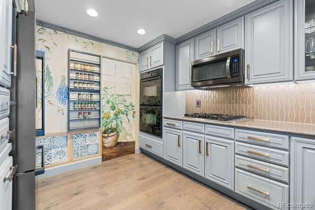 kitchen with decorative backsplash, gray cabinets, light hardwood / wood-style floors, and appliances with stainless steel finishes