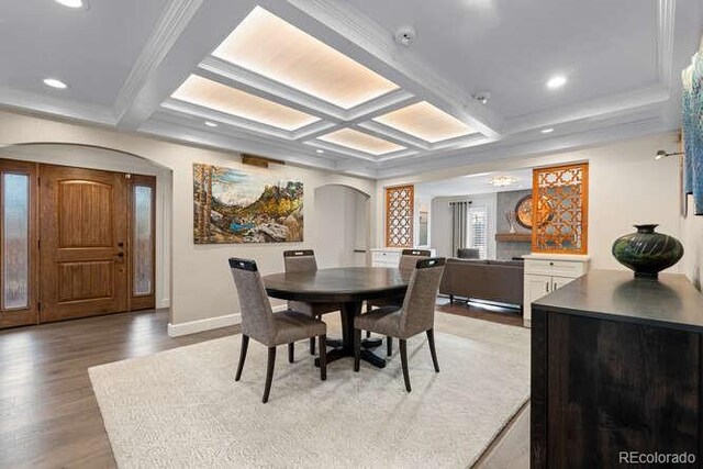 dining area with beam ceiling, hardwood / wood-style flooring, ornamental molding, and coffered ceiling