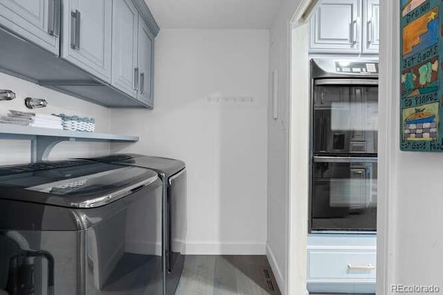 laundry area featuring cabinets, separate washer and dryer, and hardwood / wood-style flooring