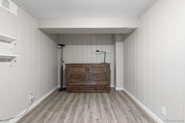 clothes washing area with light wood-type flooring and wooden walls