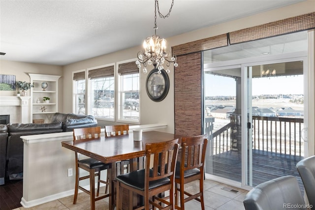 dining space with a tile fireplace, light tile patterned flooring, a textured ceiling, and a chandelier