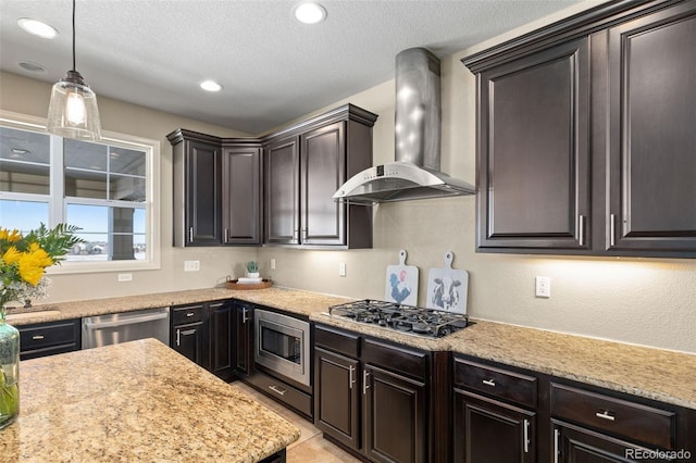 kitchen with appliances with stainless steel finishes, hanging light fixtures, dark brown cabinets, a textured ceiling, and wall chimney exhaust hood