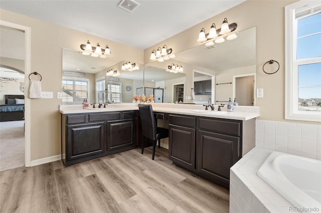 bathroom featuring hardwood / wood-style flooring, vanity, and a relaxing tiled tub