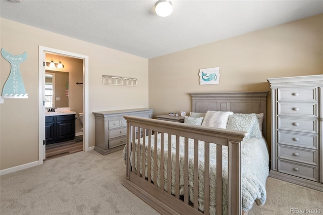 carpeted bedroom with ensuite bathroom and sink