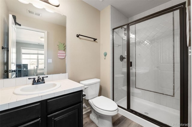 bathroom with an enclosed shower, hardwood / wood-style floors, vanity, and toilet