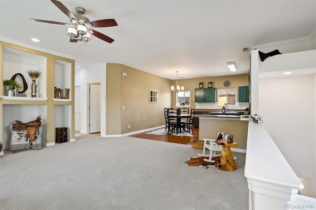 carpeted living room featuring ceiling fan with notable chandelier and ornamental molding