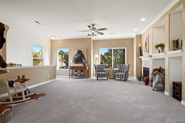 living area featuring carpet, a tile fireplace, crown molding, and ceiling fan