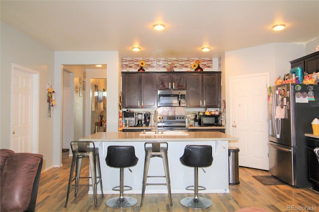 713 Indigo St, Brighton, CO 80603 - kitchen with stainless steel appliances, a kitchen bar, light countertops, and wood finished floors