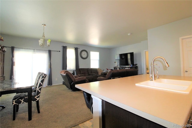 713 Indigo St, Brighton, CO 80603 - kitchen with light countertops, light colored carpet, a chandelier, a center island with sink, and pendant lighting