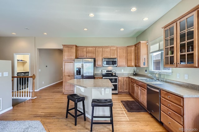 10117 Waco St, Commerce City, CO 80022 - kitchen featuring appliances with stainless steel finishes, a kitchen bar, glass insert cabinets, a center island, and recessed lighting