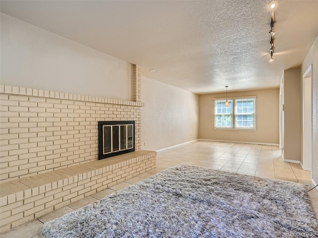 3540 E 5th Ave, Denver, CO 80206 - unfurnished living room featuring rail lighting, tile patterned flooring, a textured ceiling, a brick fireplace, and baseboards